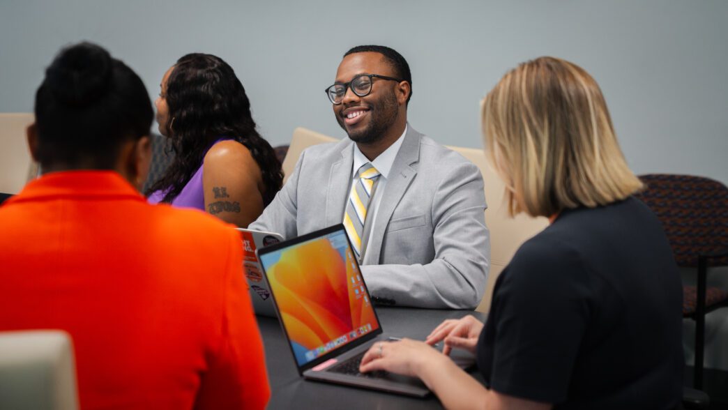 A staff member smiles around a meeting room table