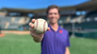 Bioengineering Ph.D. student Connor Moore holds a baseball in Doug Kingsmore Stadium