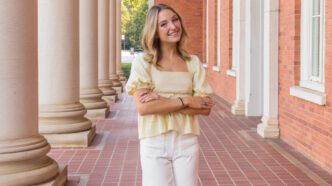 A student poses for a photograph on the steps of Sikes Hall