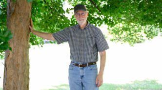 Provost Bob Jones stands on campus against a tree