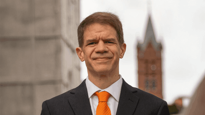 J. Cole Smith in front of academic buildings.