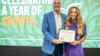 President Clements poses for a photo with Tori White, wearing a purple dress, holding her CU Grow diploma.