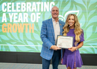 President Clements poses for a photo with Tori White, wearing a purple dress, holding her CU Grow diploma.