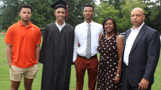 A family stands with a graduate in cap and gown