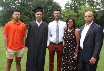 A family stands with a graduate in cap and gown