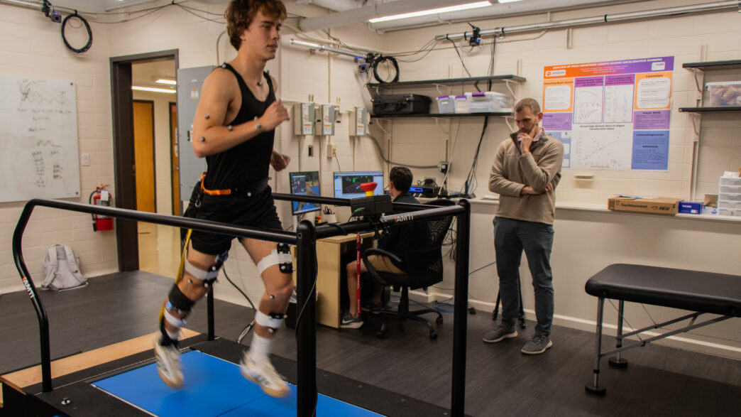 An athlete running on a treadmill with researchers in a lab