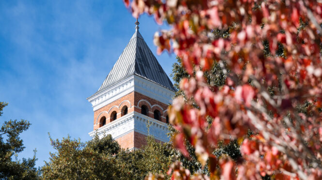 A brick tower behind red fall leaves.