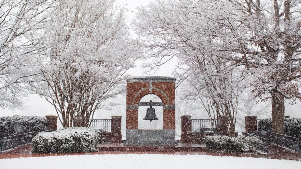 Heavy snow falling and covering trees and bushes during a winter storm on campus
