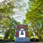 The Carillon bell stands between two large trees.