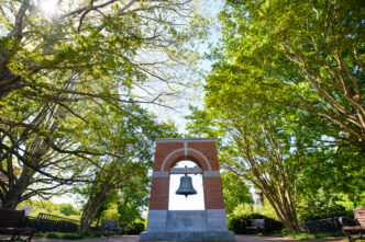 The Carillon bell stands between two large trees.