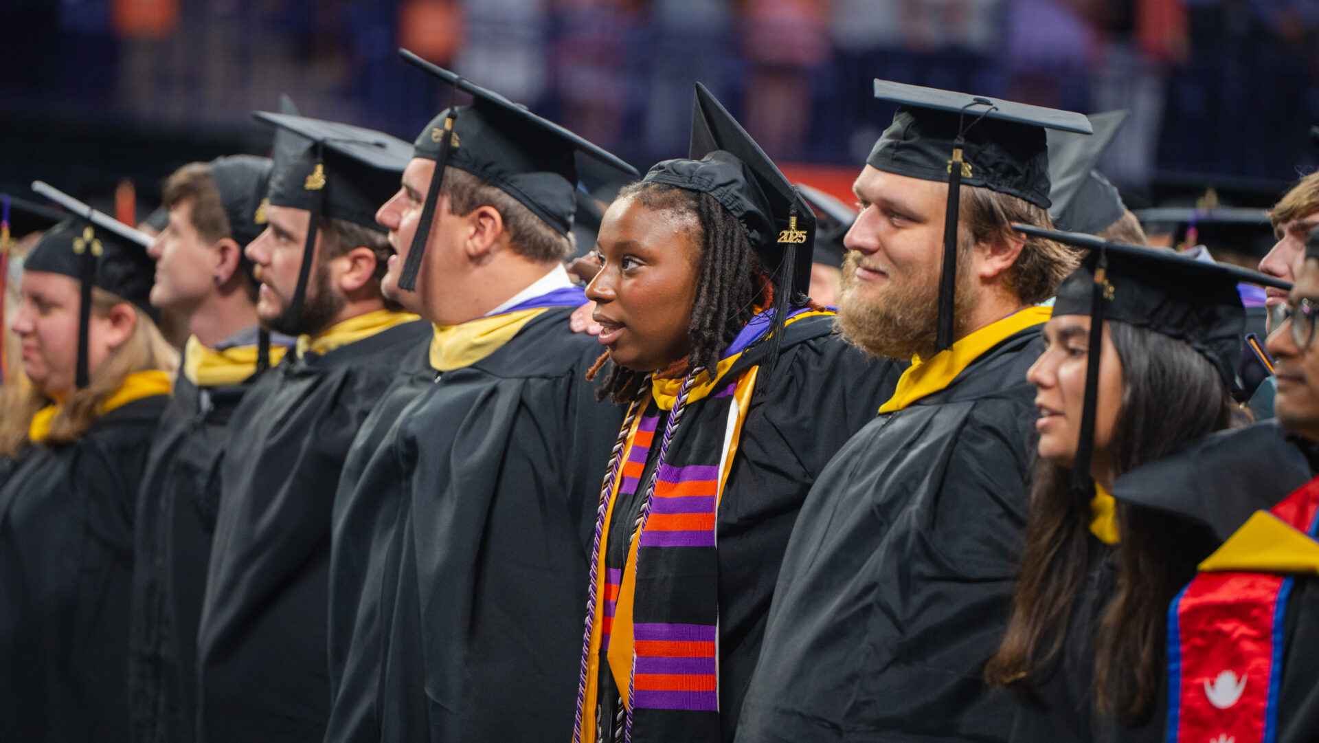 Students place their arms around each other for the singing of the Clemson alma mater during Summer Commencement in August 2025