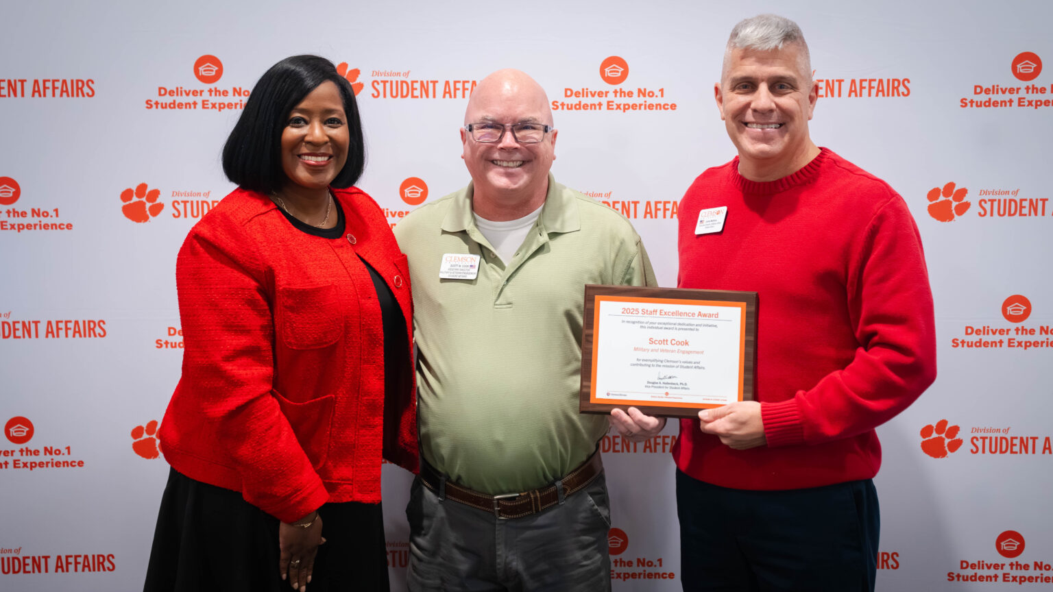 Individuals pose with an award winner in front of a Student Affairs backdrop at an awards celebration