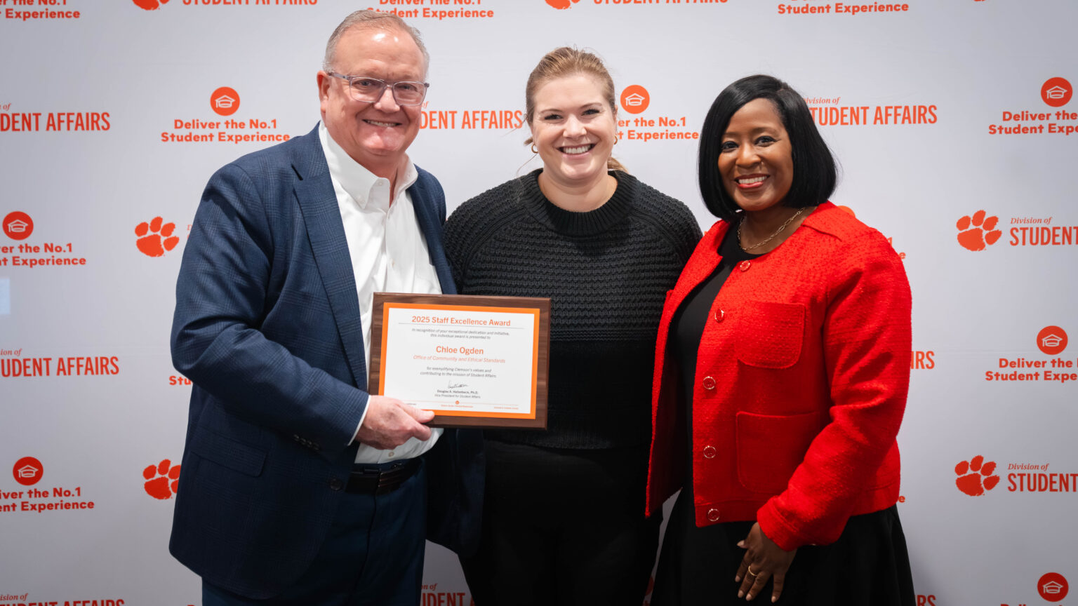Individuals pose with an award winner in front of a Student Affairs backdrop at an awards celebration