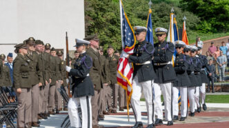 a group of soldiers in uniform holding flags and standing in a line