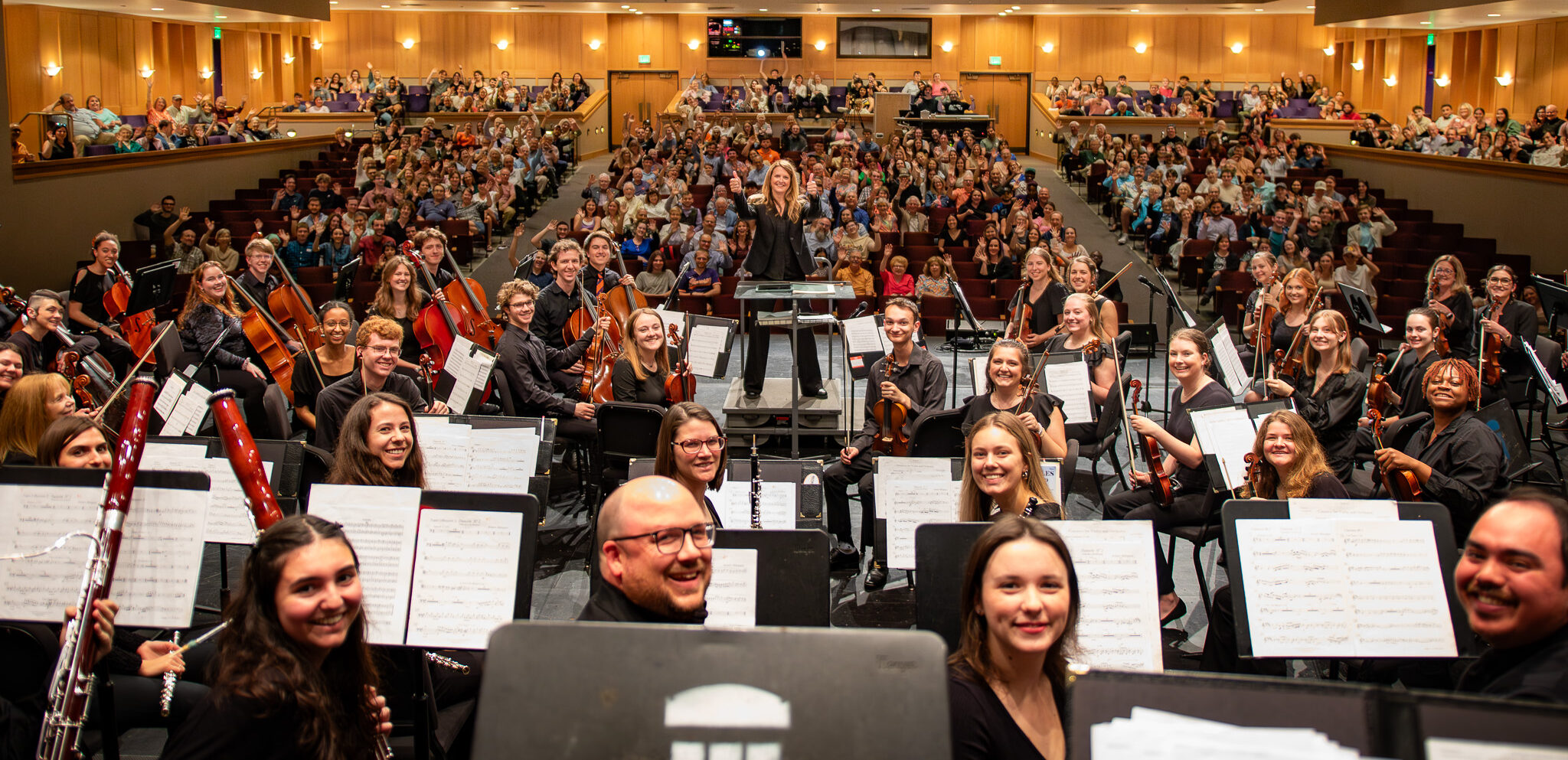 The Clemson University Symphony Orchestra pose for a selfie on stage mid-performance