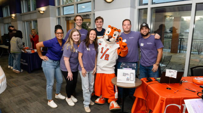 A group of individuals pose with the Tiger mascot inside a building on Clemson's campus