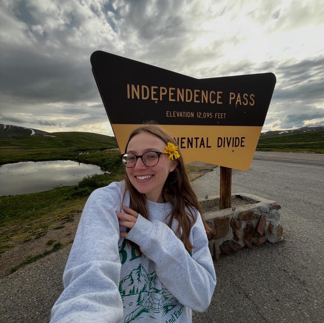 Celia Castellano takes a selfie in front of the sign for Independence Pass at the Continential Divide