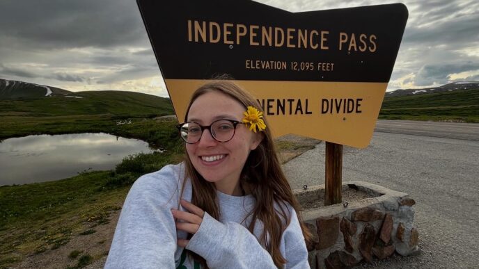 Celia Castellano takes a selfie in front of the sign for Independence Pass at the Continential Divide