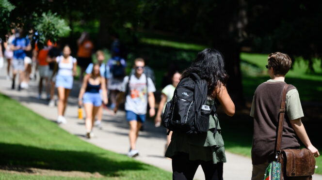 Students walking up and down a hill, wearing backpacks.