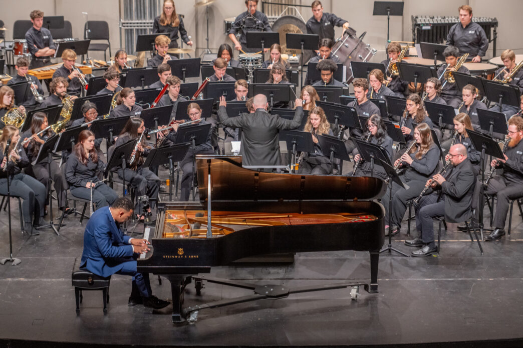 Clemson University Symphonic Band performing on stage at the Brooks Center. A pianist plays a piano downstage of the band.
