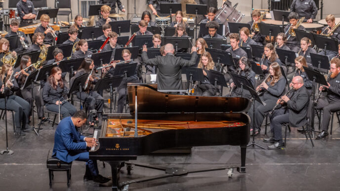 Clemson University Symphonic Band performing on stage at the Brooks Center. A pianist plays a piano downstage of the band.