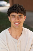 A headshot of a man wearing a beige henley shirt.