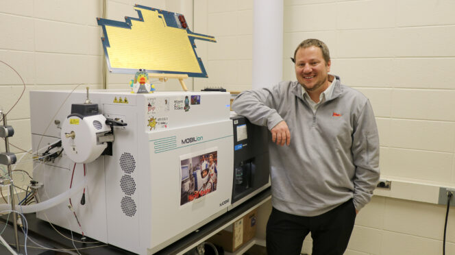 Man stands with equipment in chemistry lab