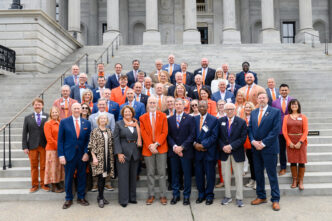 A group of individuals on the steps of the South Carolina State House in Clemson orange and purple