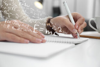 Math formulas overlaid on a photo of a person's hand writing in a notebook.
