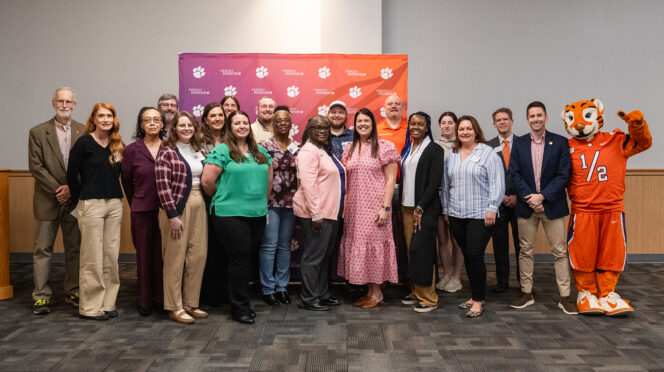 A group of staff and faculty members pose for a group photo after being recognized for earnings degrees in the past year.