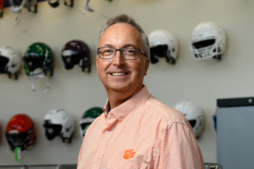 Man stands in front of wall of football helmets