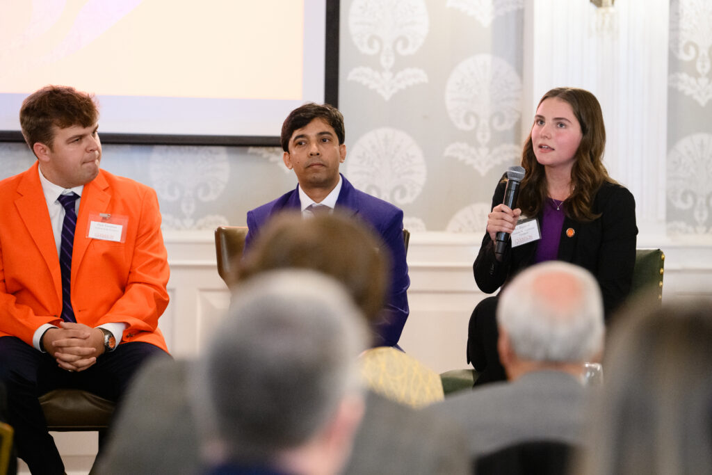 Three students sitting in chairs in a panel discussion