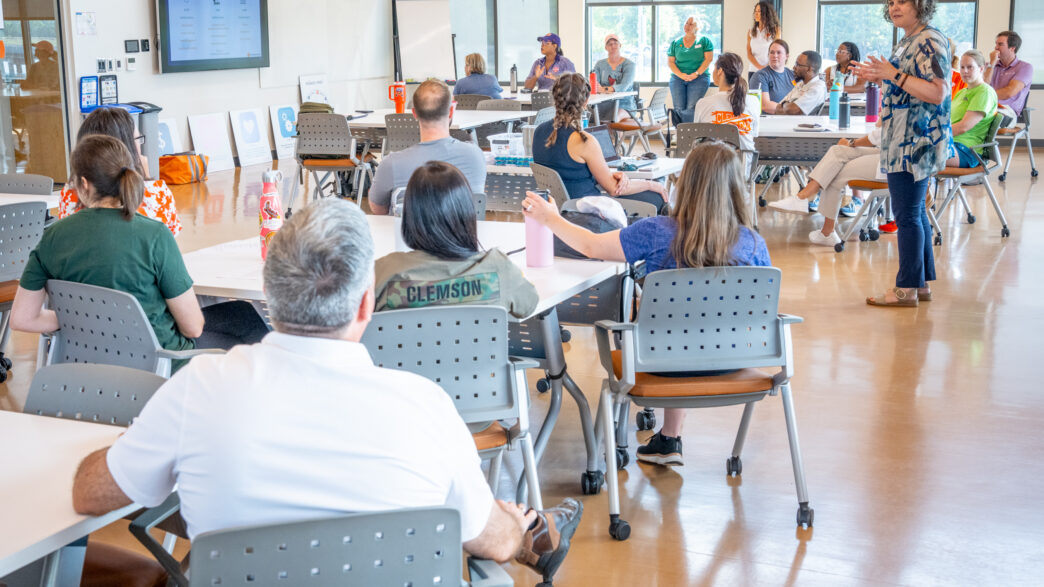 Individuals inside a classroom listening to a female speaker