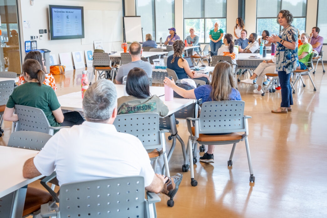Individuals inside a classroom listening to a female speaker