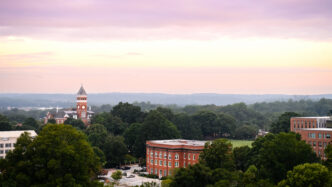 A sunrise over Clemson with Tillman Hall visible below orange and purple clouds.