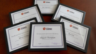 Photo of six framed certificates for the Clemson College of Science student award winners spread out on a table.