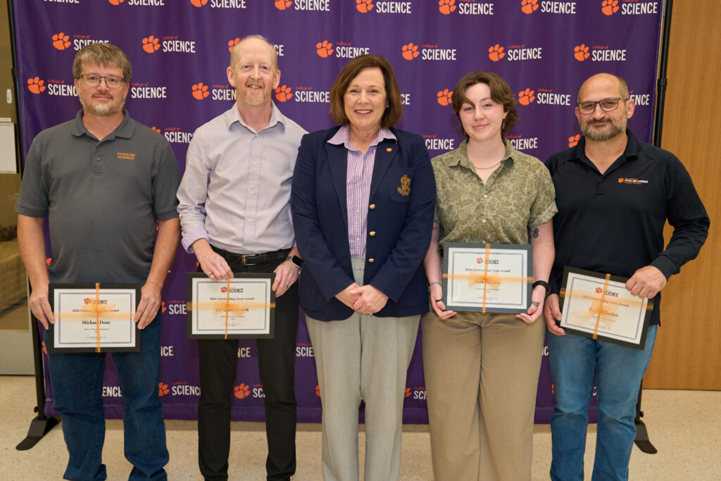 A group of five people stand in front of a banner that says College of Science and has a tiger paw. Four are holding certificates of award.