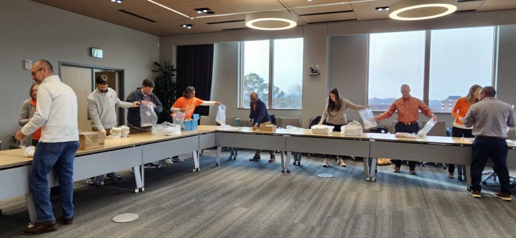 Clemson Chair Academy volunteers pack hygiene kits at long tables.