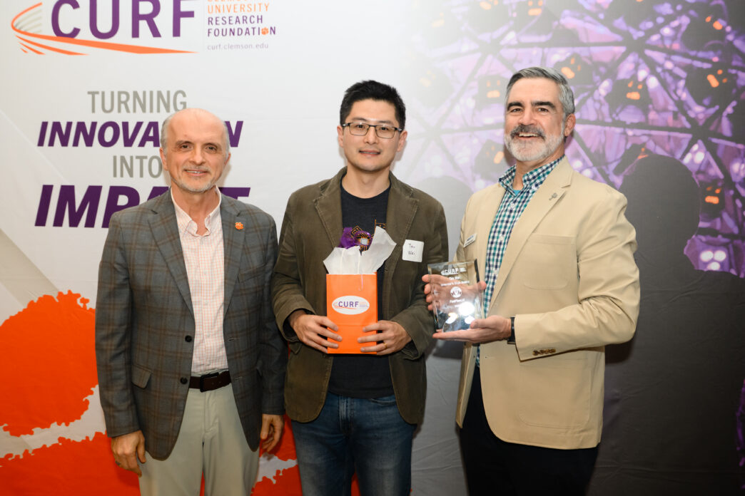 Three men in suit jackets pose for a photo