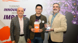 Three men in suit jackets pose for a photo