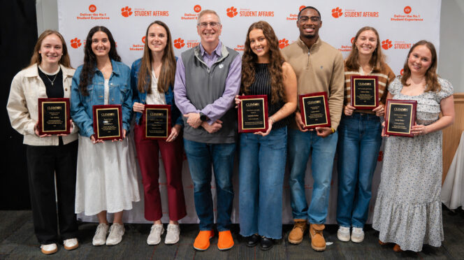 Students hold 2026 award plaques flanked by Vice President for Student Affairs Doug Hallenbeck