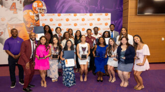 A group of individuals holding awards and certificates in front of a backdrop