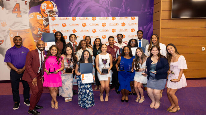 A group of individuals holding awards and certificates in front of a backdrop