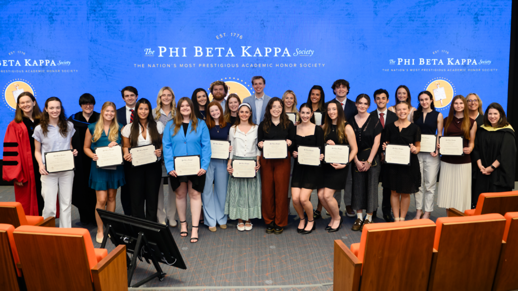 A group of people smiling in front of a blue banner that says "Phi Beta Kappa"