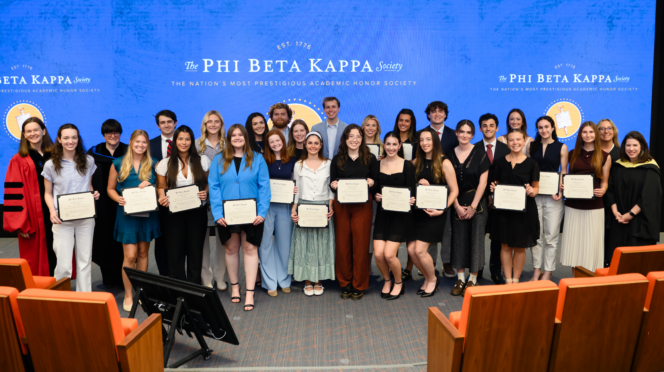 A group of people smiling in front of a blue banner that says "Phi Beta Kappa"