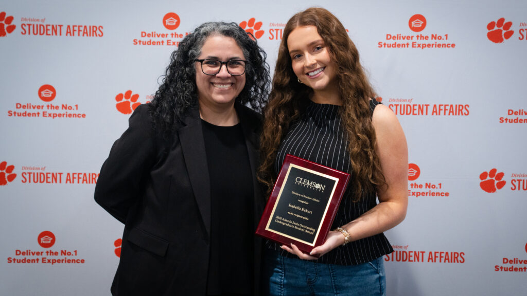 A student holds an award plaque alongside Sara Dawson of Counseling and Psychological Services