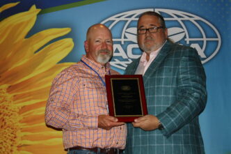 Brad Stancil stands on the left smiling as he receives an awards plaque from AOSCA president Billy Skaggs.