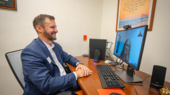 A male in a suit speaks to a female on a virtual call