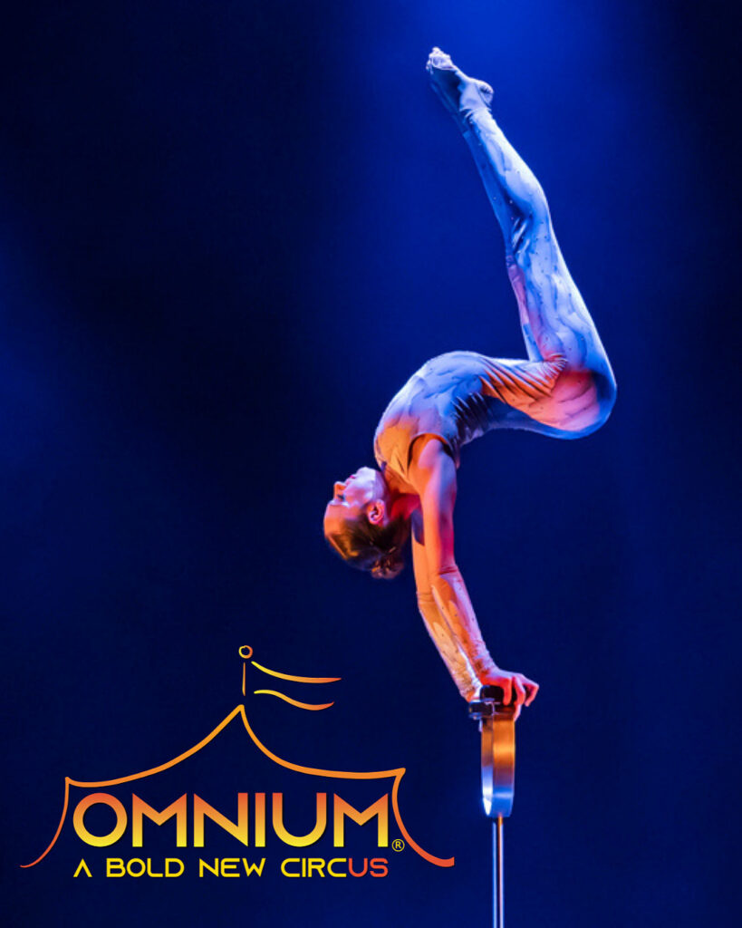 An acrobat performs a one-arm handstand contortion under blue stage lighting beside the “OMNIUM: A Bold New Circus” logo.