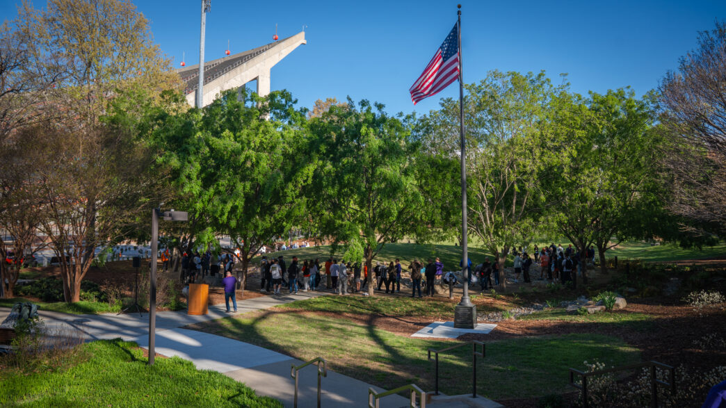 Attendees circle a large mound at the Scroll of Honor Memorial